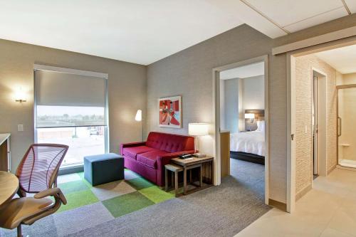 a hotel room with a red couch and a bed at Home2 Suites By Hilton Montreal Dorval in Dorval