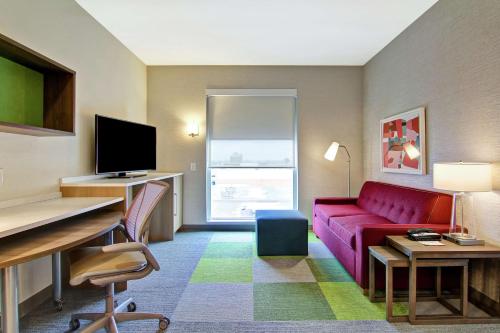 a hotel room with a red couch and a desk at Home2 Suites By Hilton Montreal Dorval in Dorval