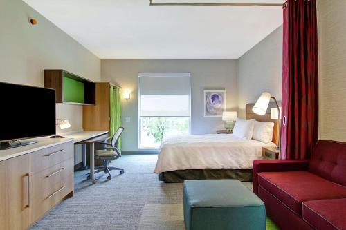 a hotel room with a bed and a desk at Home2 Suites By Hilton Montreal Dorval in Dorval