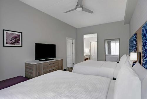 a bedroom with two beds and a flat screen tv at Homewood Suites by Hilton London Ontario in London