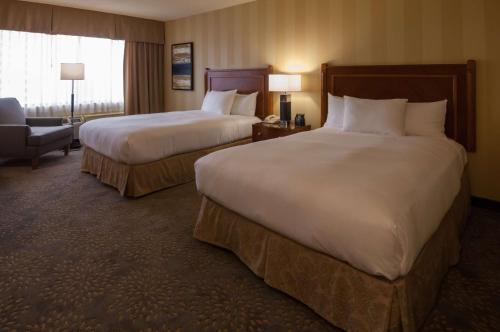 a hotel room with two beds and a chair at Doubletree by Hilton London in London