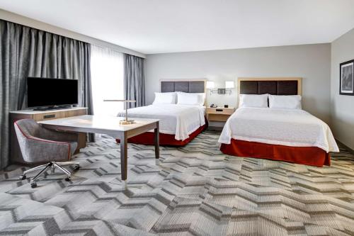 a hotel room with two beds and a flat screen tv at Hampton Inn & Suites - Medicine Hat in Medicine Hat