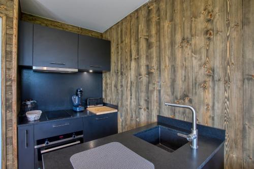 - une cuisine avec un évier et un mur en bois dans l'établissement Le domaine du Pech Eternel, à Sarlat-la-Canéda