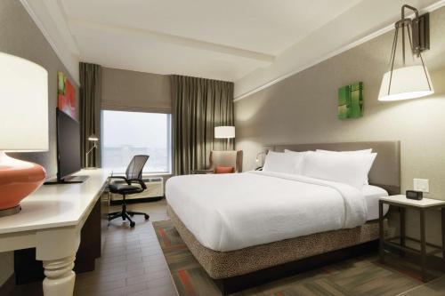 a hotel room with a large white bed and a desk at Hilton Garden Inn Calgary Downtown in Calgary