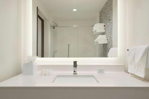 a white bathroom with a sink and a mirror at Hilton Garden Inn Calgary Downtown in Calgary