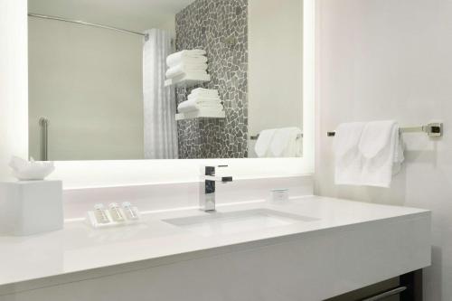 a white bathroom with a sink and a mirror at Hilton Garden Inn Calgary Downtown in Calgary