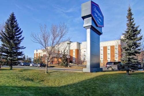 a clock tower in the grass in front of a building at Hampton Inn & Suites by Hilton Calgary-Airport in Calgary