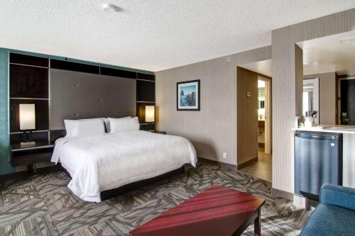 Habitación de hotel con cama y sala de estar. en Hampton Inn & Suites by Hilton Calgary-Airport, en Calgary