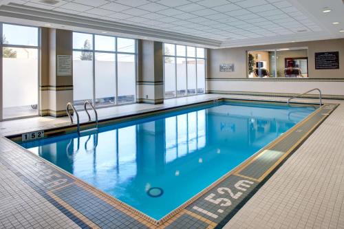 - une grande piscine d'eau bleue dans un bâtiment dans l'établissement Hampton Inn & Suites by Hilton Toronto Airport, à Mississauga