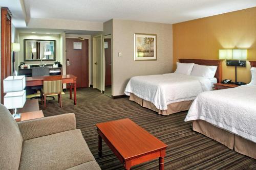 a hotel room with two beds and a desk at Hampton Inn & Suites by Hilton Toronto Airport in Mississauga
