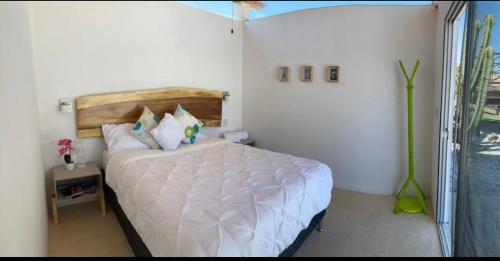 a bedroom with a white bed with a wooden headboard at Glamping Risco Xodhe Cactus in Tecozautla