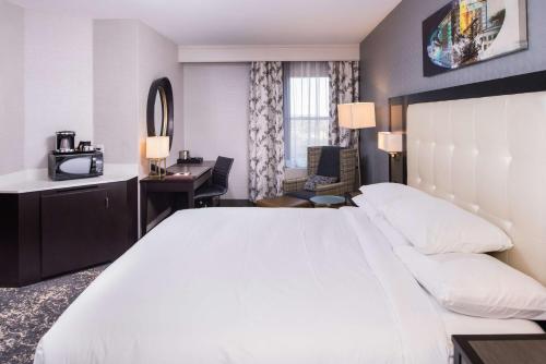 a hotel room with a large white bed and a desk at DoubleTree by Hilton Utica in Utica