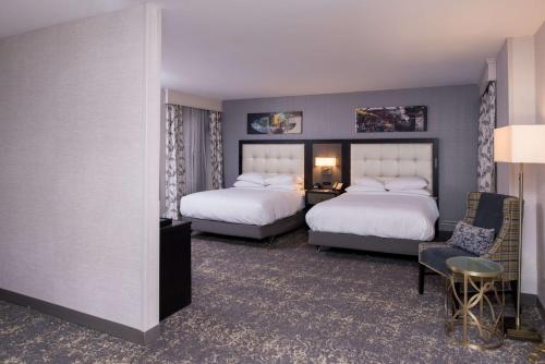 a hotel room with two beds and a chair at DoubleTree by Hilton Utica in Utica