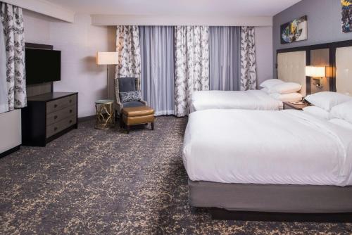 a hotel room with two beds and a flat screen tv at DoubleTree by Hilton Utica in Utica