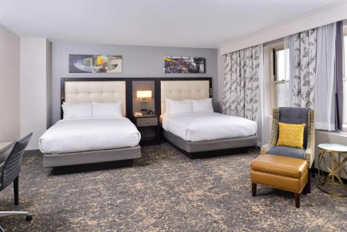 a hotel room with two beds and a chair at DoubleTree by Hilton Utica in Utica
