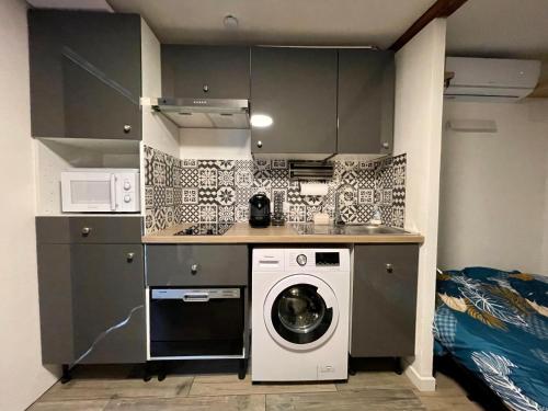 een keuken met een wasmachine en een wasmachine bij Studio au calme climatisé avec terrasse in Paillet