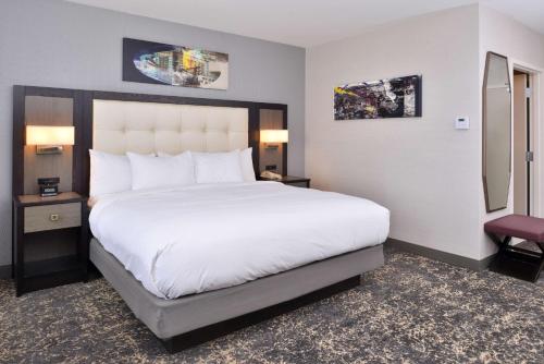 a hotel room with a large bed with white sheets at DoubleTree by Hilton Utica in Utica