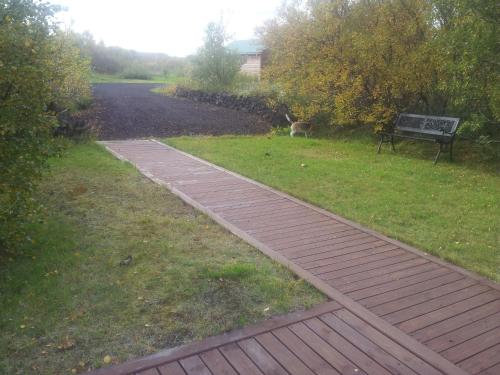 a walkway in a park with a bench and a dog at Vetursetur in Laxamýri