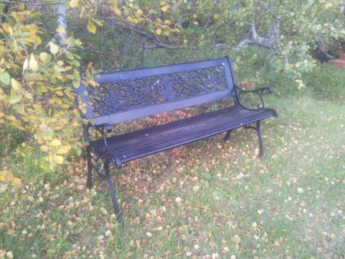 a black park bench sitting in the grass at Vetursetur in Laxamýri