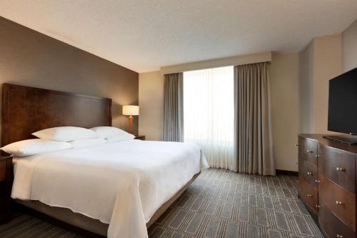 a hotel room with a large bed and a window at Embassy Suites by Hilton Chicago Lombard in Lombard