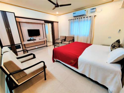 Shradha luxury room في كالانغيُت: غرفة نوم بسرير وكرسي وتلفزيون