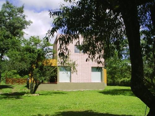 a building in a field of green grass with trees at Cabañas Mayma in Vaqueros