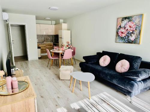 Una sala de estar con un sofá negro y una mesa. en Apartment Perla - АТЕА Complex, en Kavarna