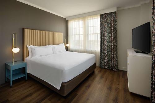 a bedroom with a large white bed and a television at The Terrace Hotel Lakeland, Tapestry Collection by Hilton in Lakeland