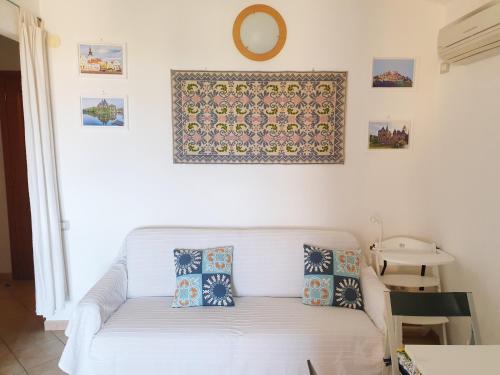un divano bianco in soggiorno con un orologio sul muro di Sun & Beach house Costa Rei a Costa Rei