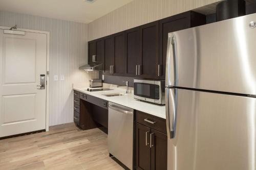 a kitchen with a stainless steel refrigerator and wooden cabinets at Homewood Suites by Hilton Needham Boston in Needham