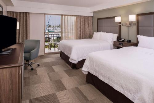 a hotel room with two beds and a flat screen tv at Hampton Inn Channel Islands Harbor in Oxnard