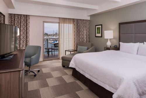 ein Hotelzimmer mit einem Bett, einem Schreibtisch und einem TV in der Unterkunft Hampton Inn Channel Islands Harbor in Oxnard