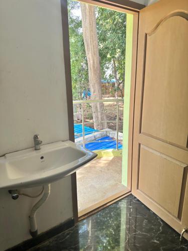 een badkamer met een wastafel en een open deur bij YUGA GUEST HOUSE in Kuttālam