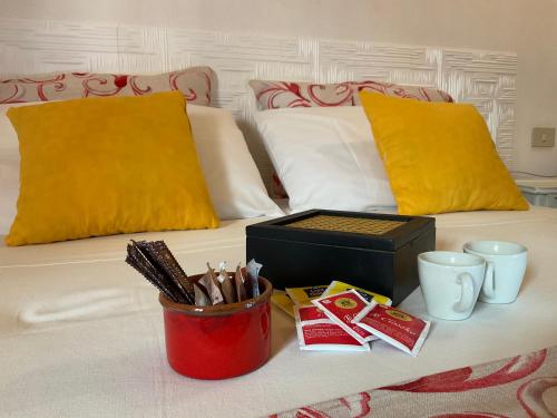 a bed with yellow and white pillows and a container of pens at Un Nido Tra Mare e Monti in Partinico
