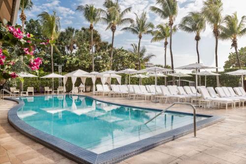 uma piscina com cadeiras e guarda-sóis num resort em Hilton Bentley Miami South Beach em Miami Beach