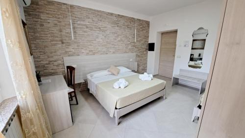 a bedroom with a white bed and a brick wall at Hera Tropea Rooms in Tropea