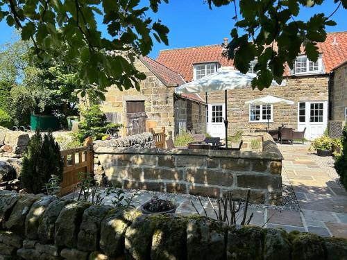 a stone house with a stone wall and a yard at Smugglers Rock Cottages in Ravenscar