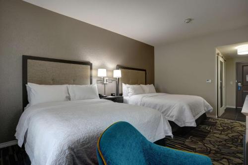 a hotel room with two beds and a blue chair at Hampton Inn & Suites Ardmore in Ardmore