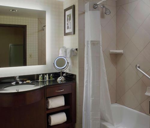 a bathroom with a sink and a tub and a mirror at DoubleTree Suites by Hilton Bentonville in Bentonville