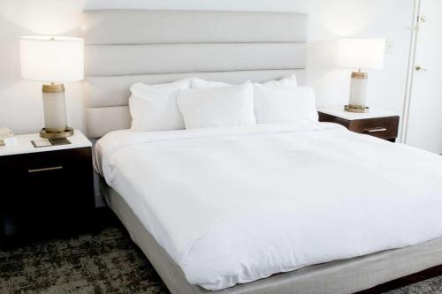 a bedroom with a large white bed with two lamps at DoubleTree by Hilton Charlottesville in Charlottesville