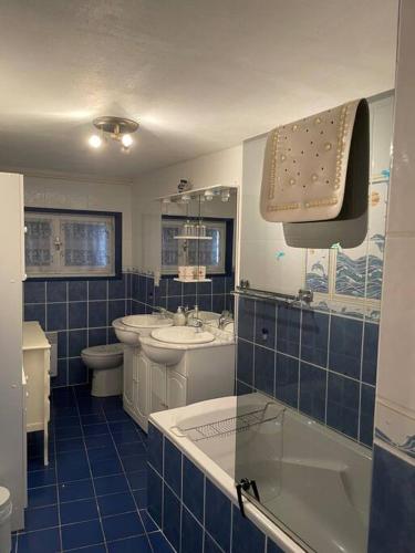 La salle de bains est pourvue de carrelage bleu, d'un lavabo et de toilettes. dans l'établissement Family friendly house in Brenac, à Quillan