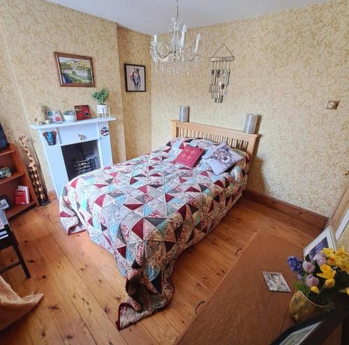 um quarto com uma cama com uma colcha e uma lareira em Room in a Cosy Cottage close to Cardiff City Centre 