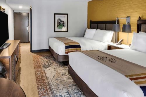 a hotel room with two beds and a desk at Estancia del Norte San Antonio, A Tapestry Hotel by Hilton in San Antonio