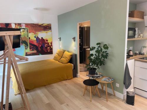 a bedroom with a yellow bed and a kitchen at Studio Au Clair de Lune in Saint-Alban-de-Roche