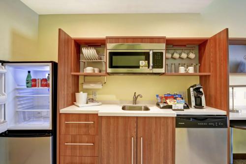 a kitchen with a sink and a microwave and a refrigerator at Home2 Suites by Hilton Charlotte Airport in Charlotte