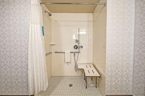 a walk in shower with a bench in a bathroom at Hampton Inn Fresno Airport in Fresno