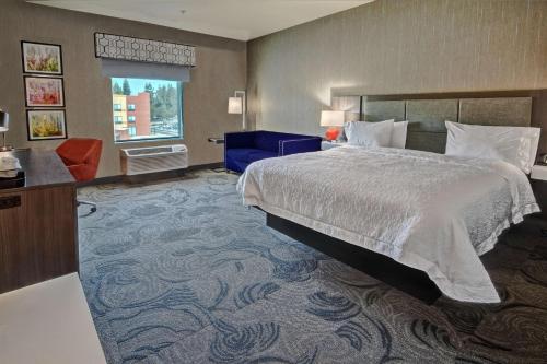 um quarto de hotel com uma cama e uma cadeira azul em Hampton Inn Fresno Airport em Fresno
