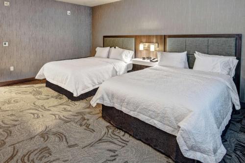 a hotel room with two beds with white sheets at Hampton Inn Fresno Airport in Fresno