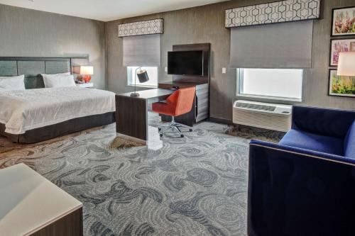 a hotel room with a bed and a desk and a television at Hampton Inn Fresno Airport in Fresno