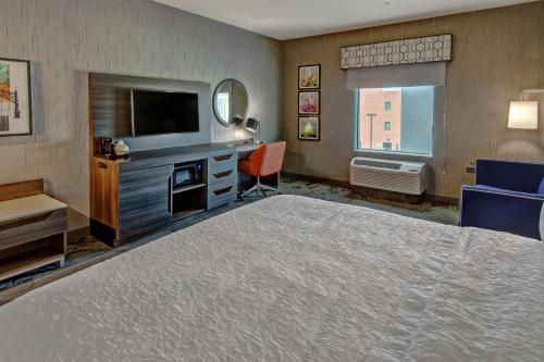 a hotel room with a large bed and a television at Hampton Inn Fresno Airport in Fresno